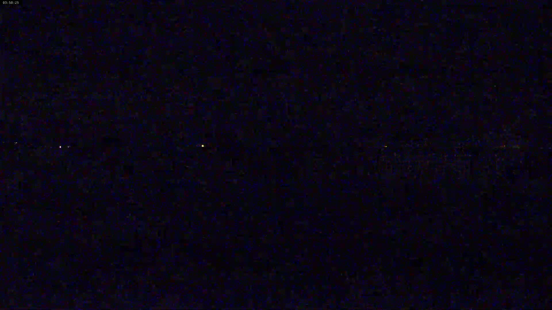 A dark, nighttime scene shows a few faint, distant lights on the horizon.