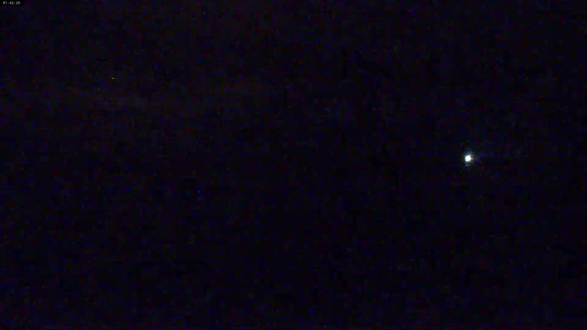 A bright light is visible in a dark night sky.