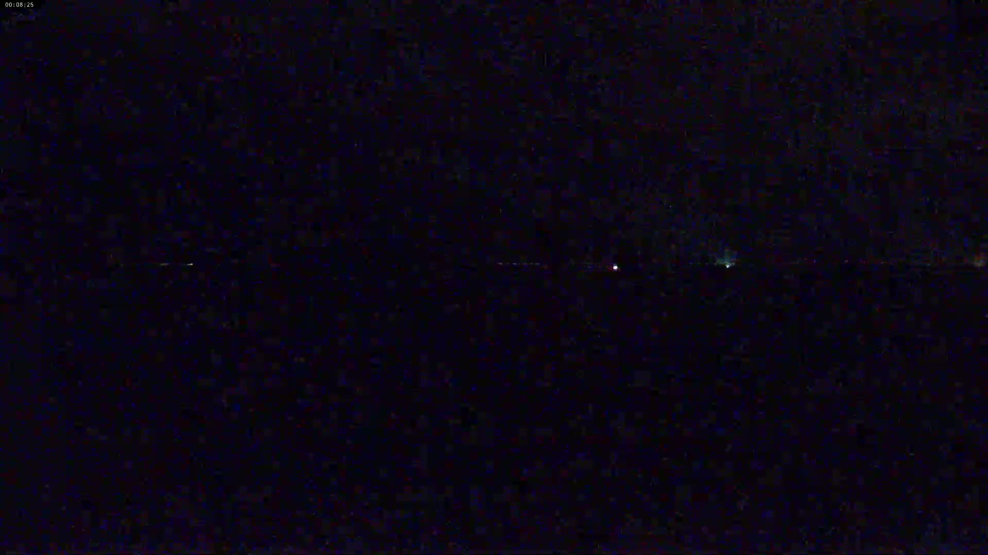 A nighttime long shot shows a dark, seemingly flat horizon with a few faint, distant lights.