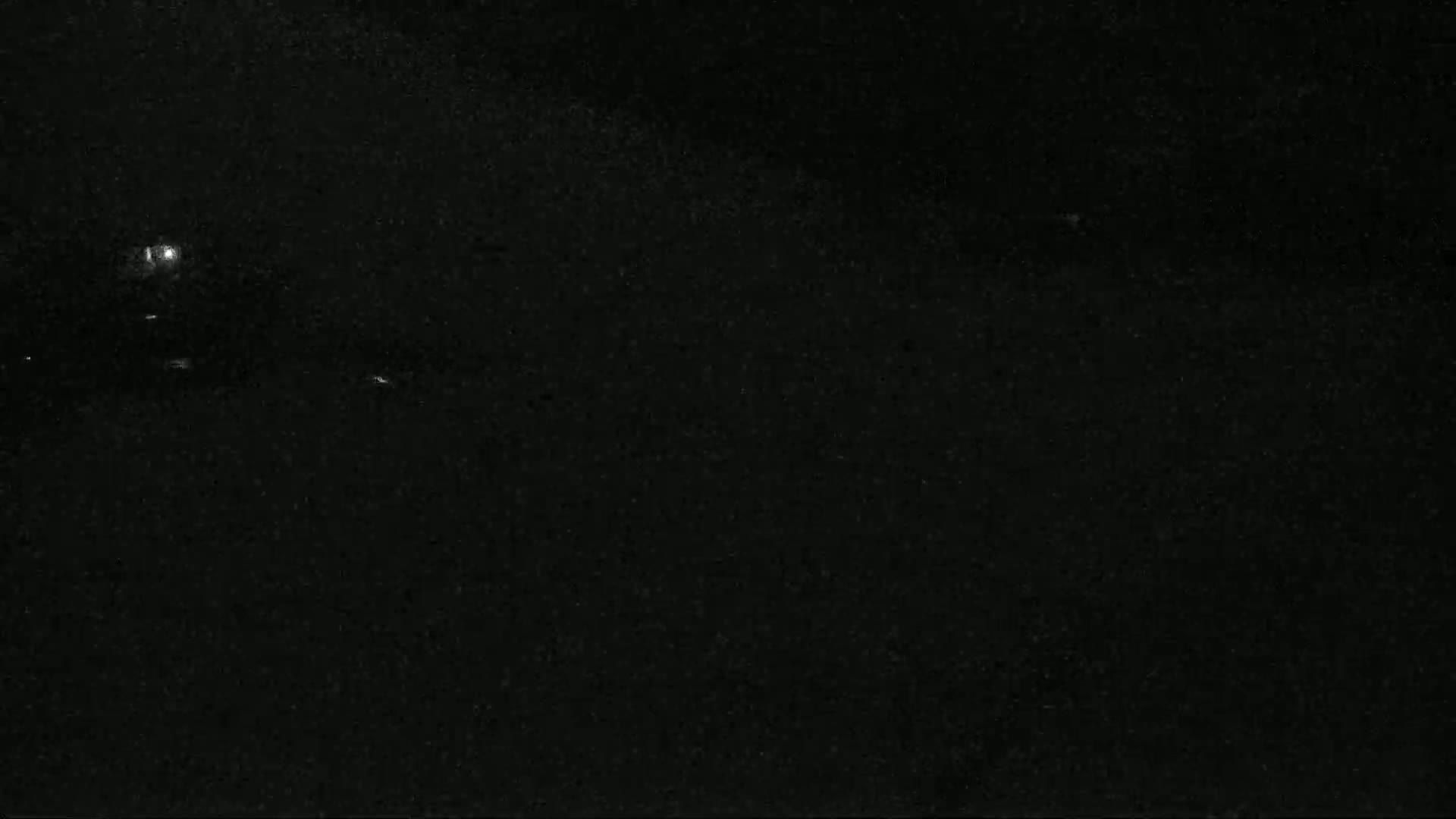 A nighttime, dark image shows faint lights in the distance and a grainy texture.