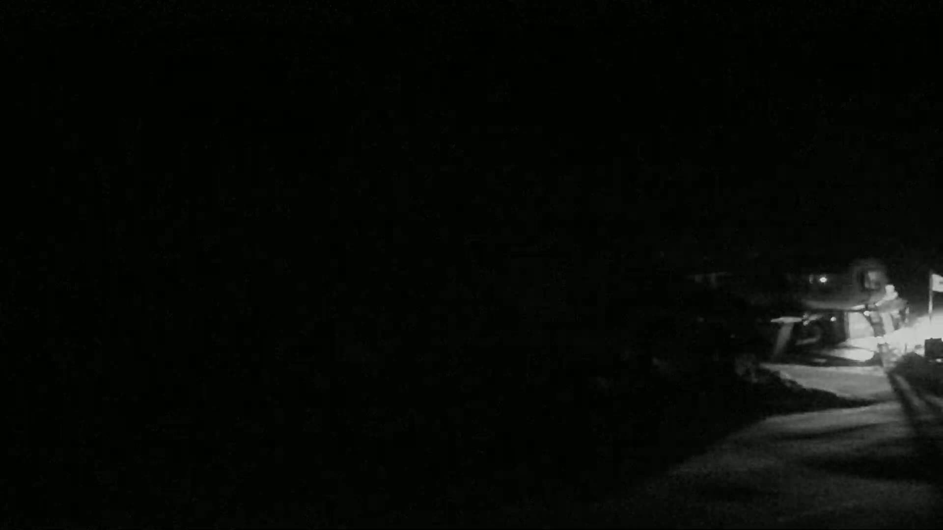 A dimly lit nighttime scene shows a vehicle and a person standing nearby.