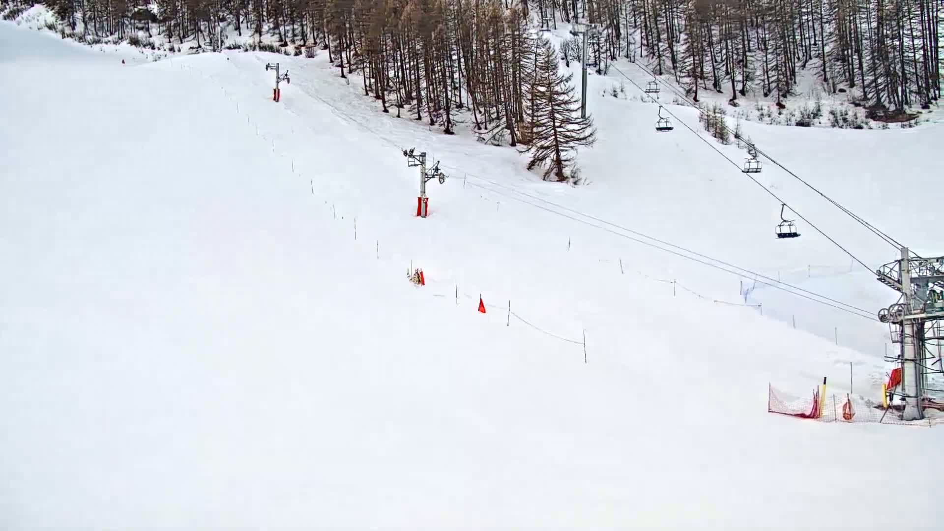 A snow-covered ski slope with chairlifts and red markers is visible in a wintery scene.