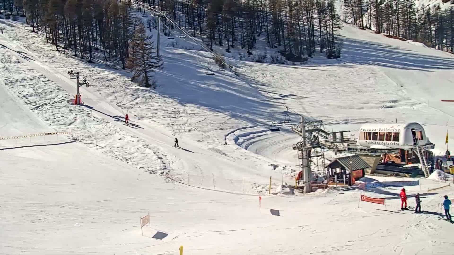 A sunny ski slope with a chairlift and several skiers.