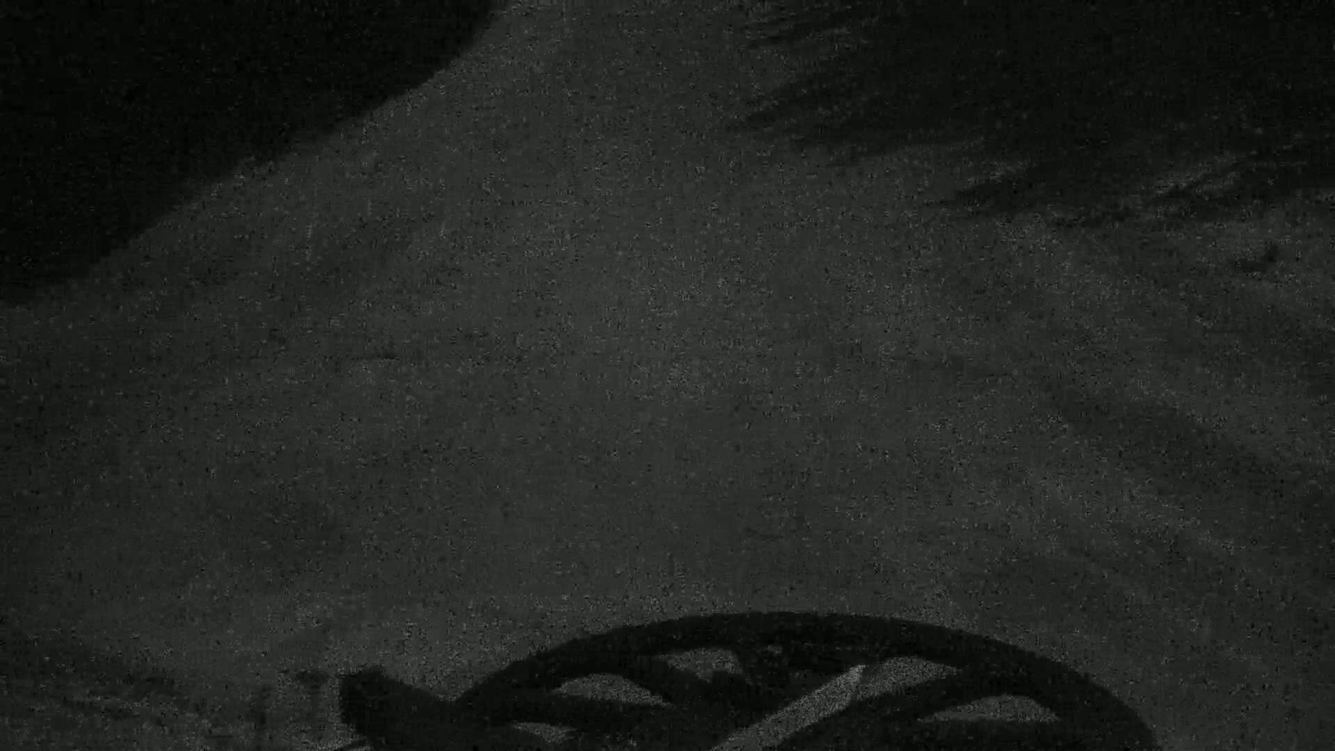 A dark, grainy surface shows the shadow of a bicycle wheel at the bottom.