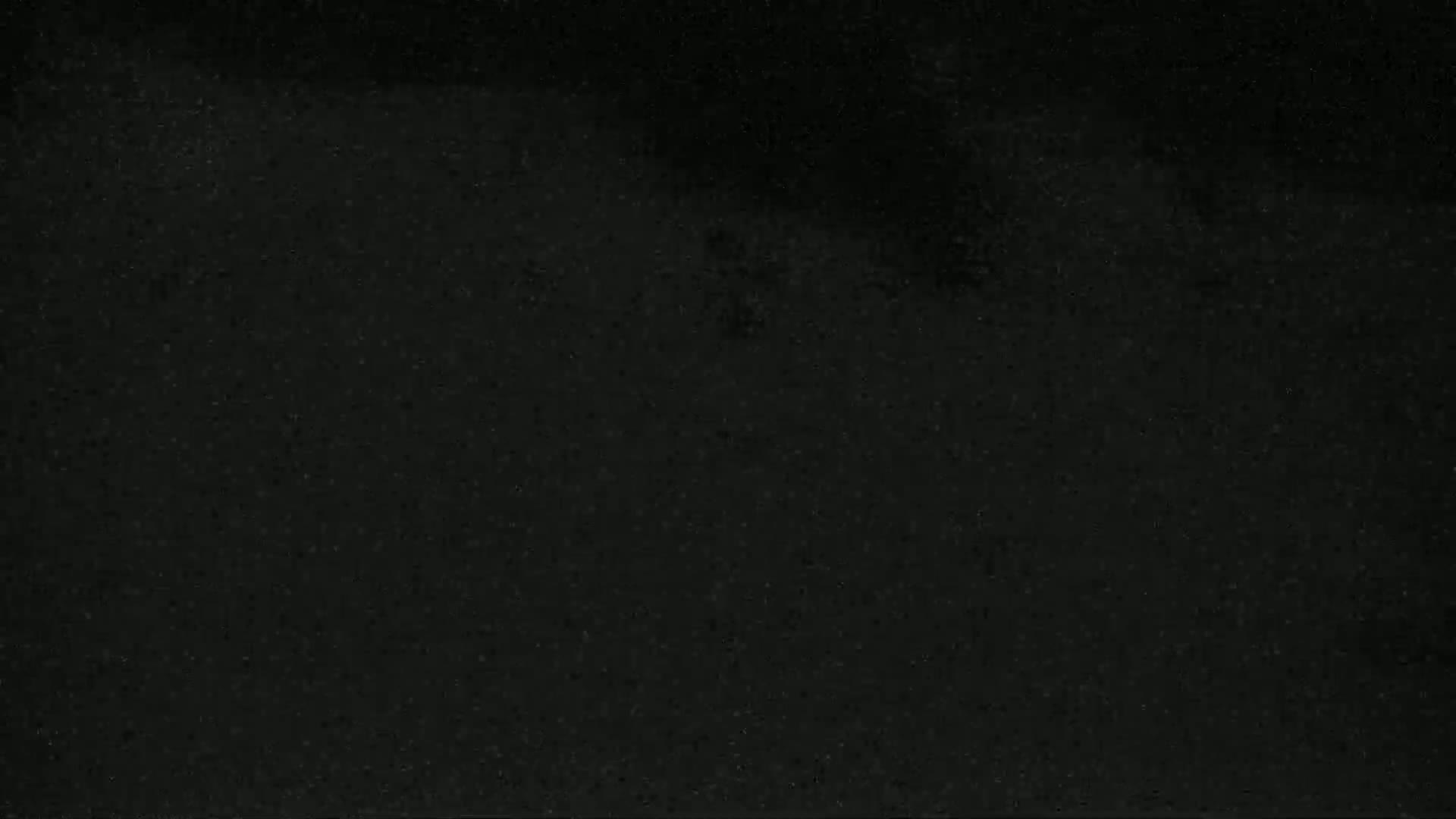 The image shows a dark, textured surface that appears to be either asphalt or dark-colored stone.