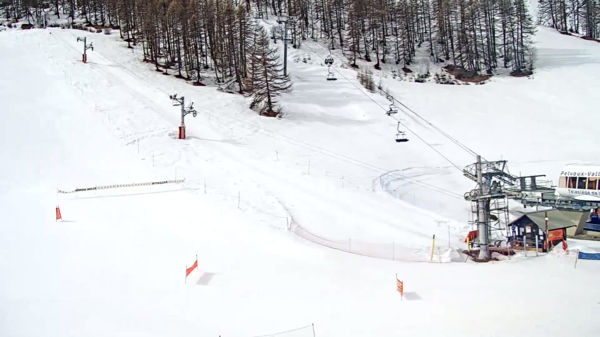 A snow-covered ski slope with several chairlifts and markers is visible, surrounded by a coniferous forest.