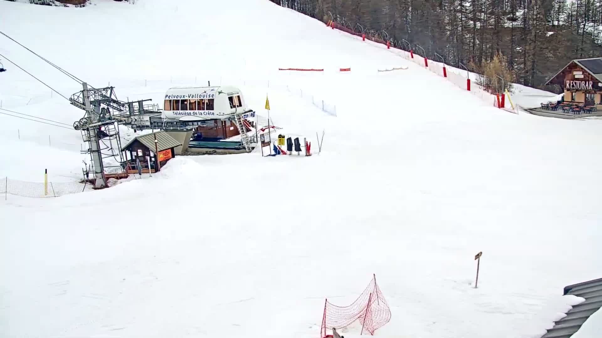 A chairlift station and a snow-covered ski slope are visible in a snowy, outdoor setting.