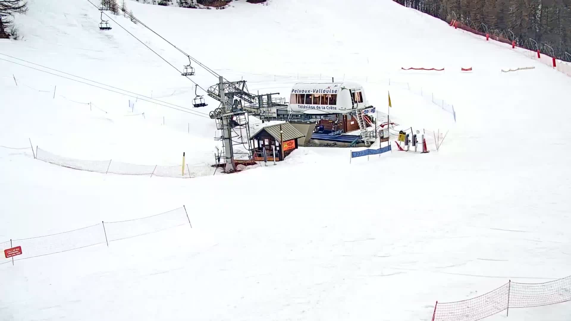 A ski lift station sits on a snow-covered ski slope on an overcast day.