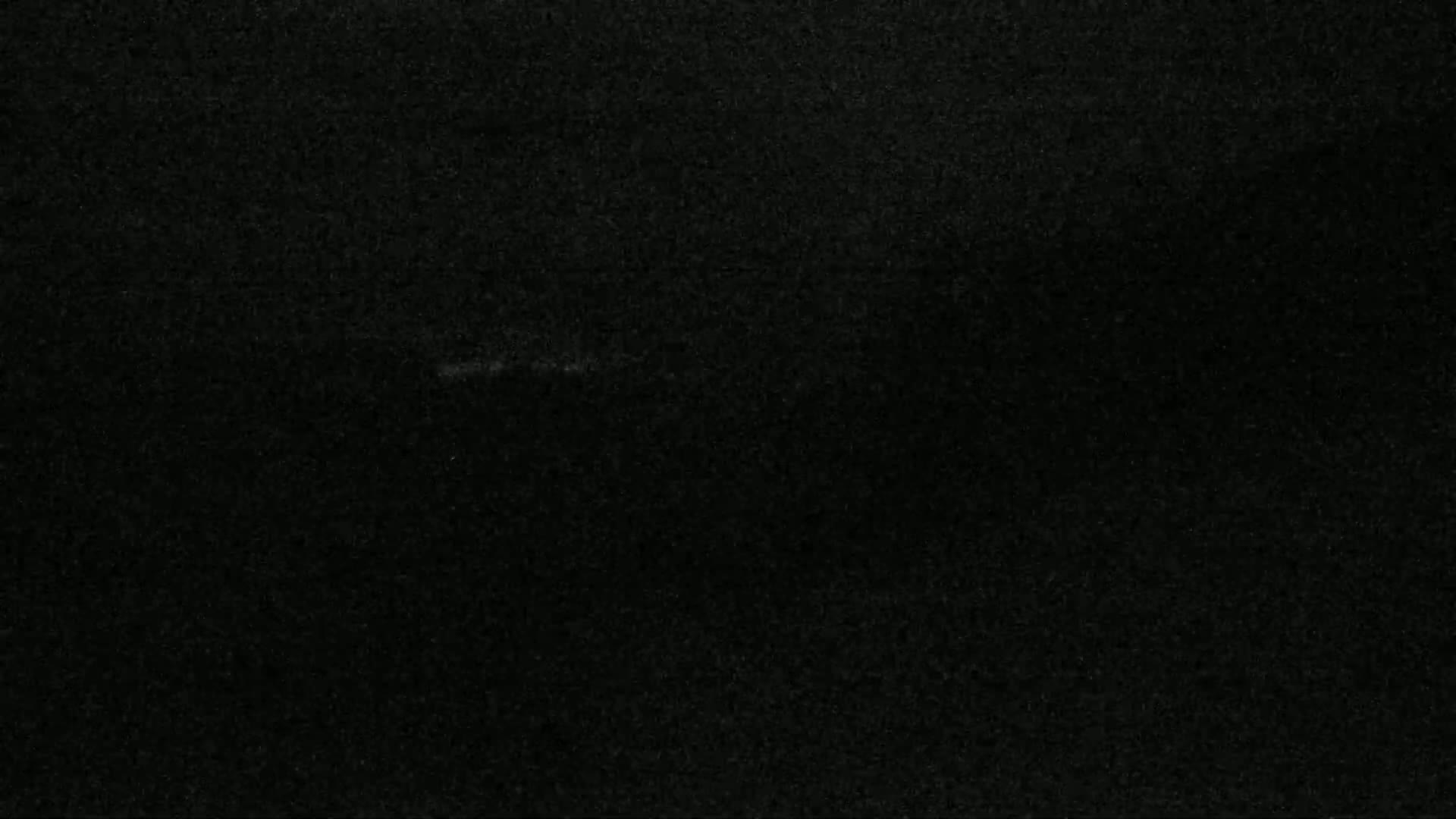 The image shows a dark, textured surface that appears to be a piece of dark-colored fabric or paper.