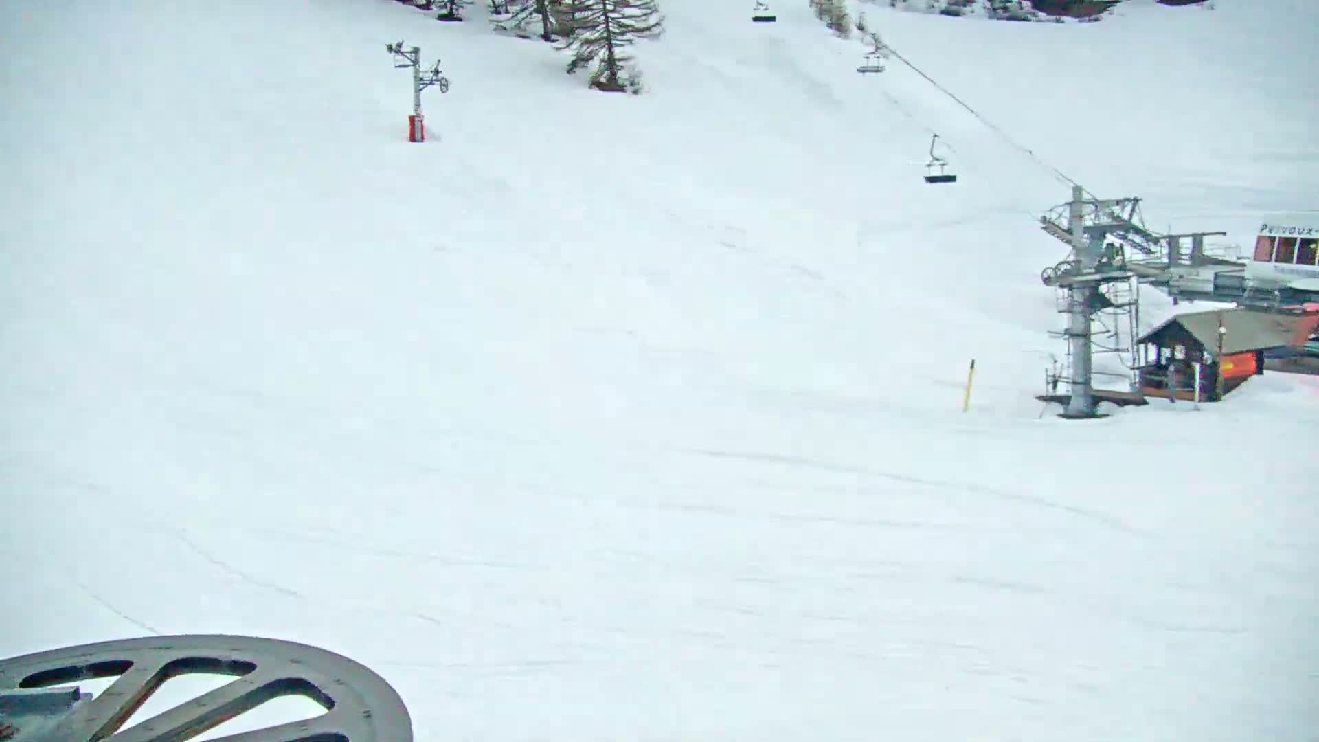 A snow-covered ski slope with ski lifts and a small building is visible under an overcast sky.