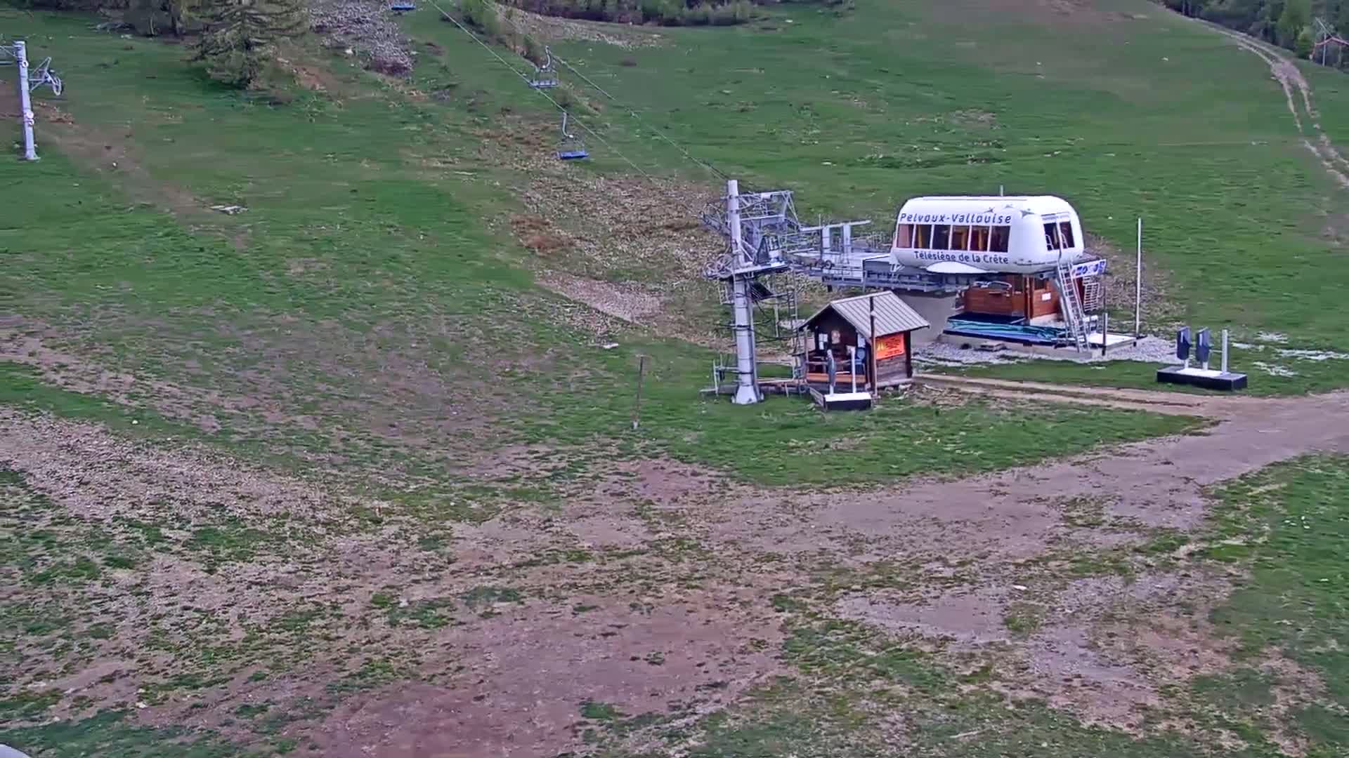 A chairlift station sits on a grassy hillside under a clear sky.