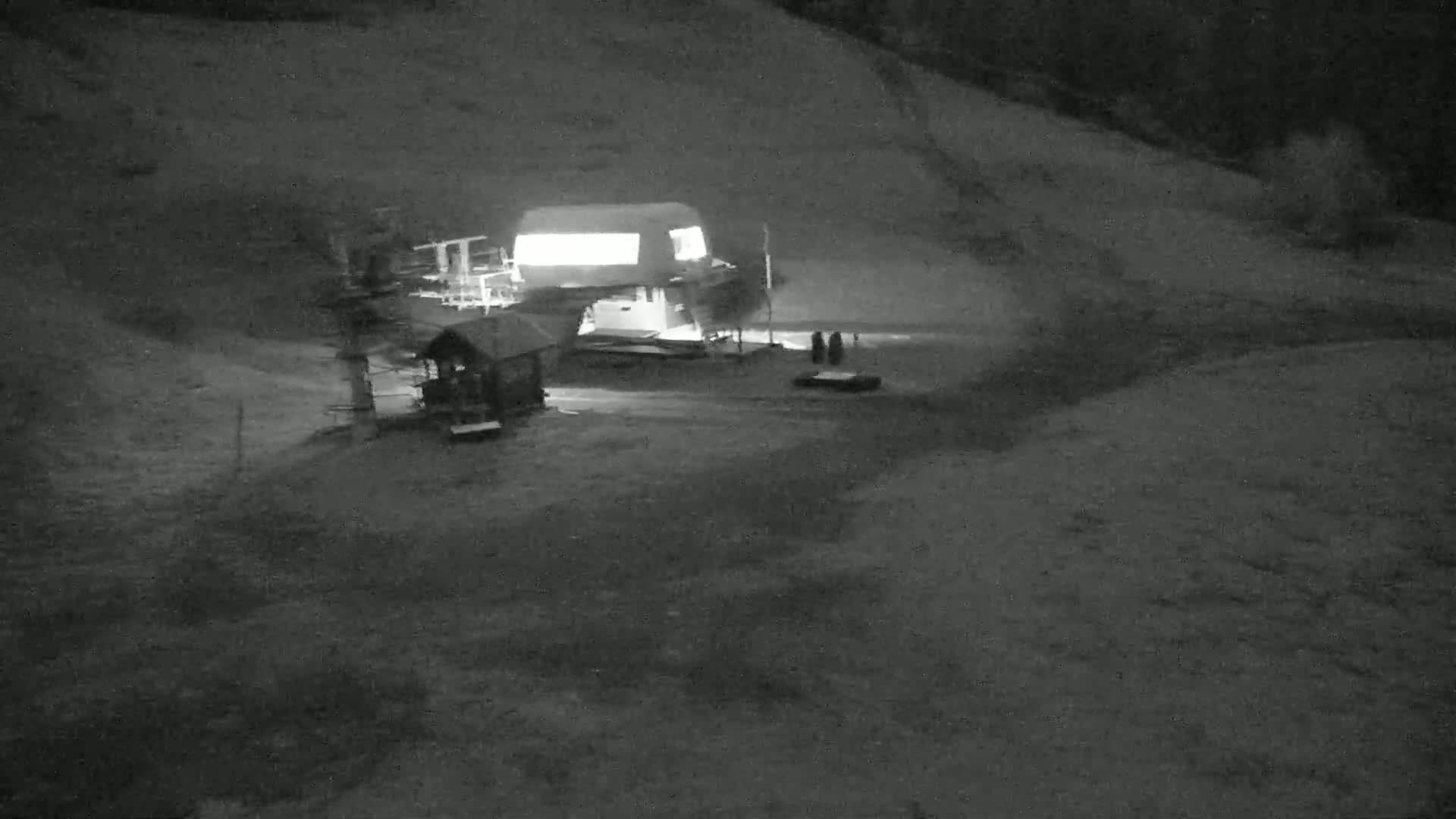 A nighttime, low-light view shows a ski lift station at the base of a hill.