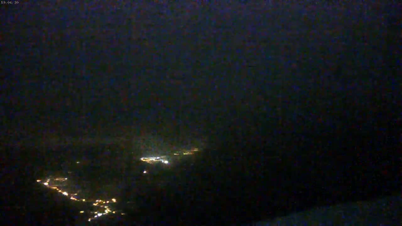 Faintly lit areas of land are visible from a high vantage point at night under a dark, possibly cloudy sky.