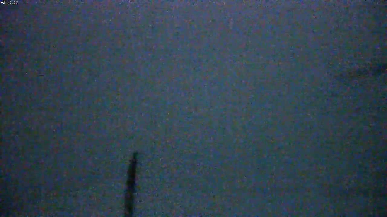 A dark, blurry image shows a thin, dark vertical line in the center against a mostly uniform, dark-blue-gray background.