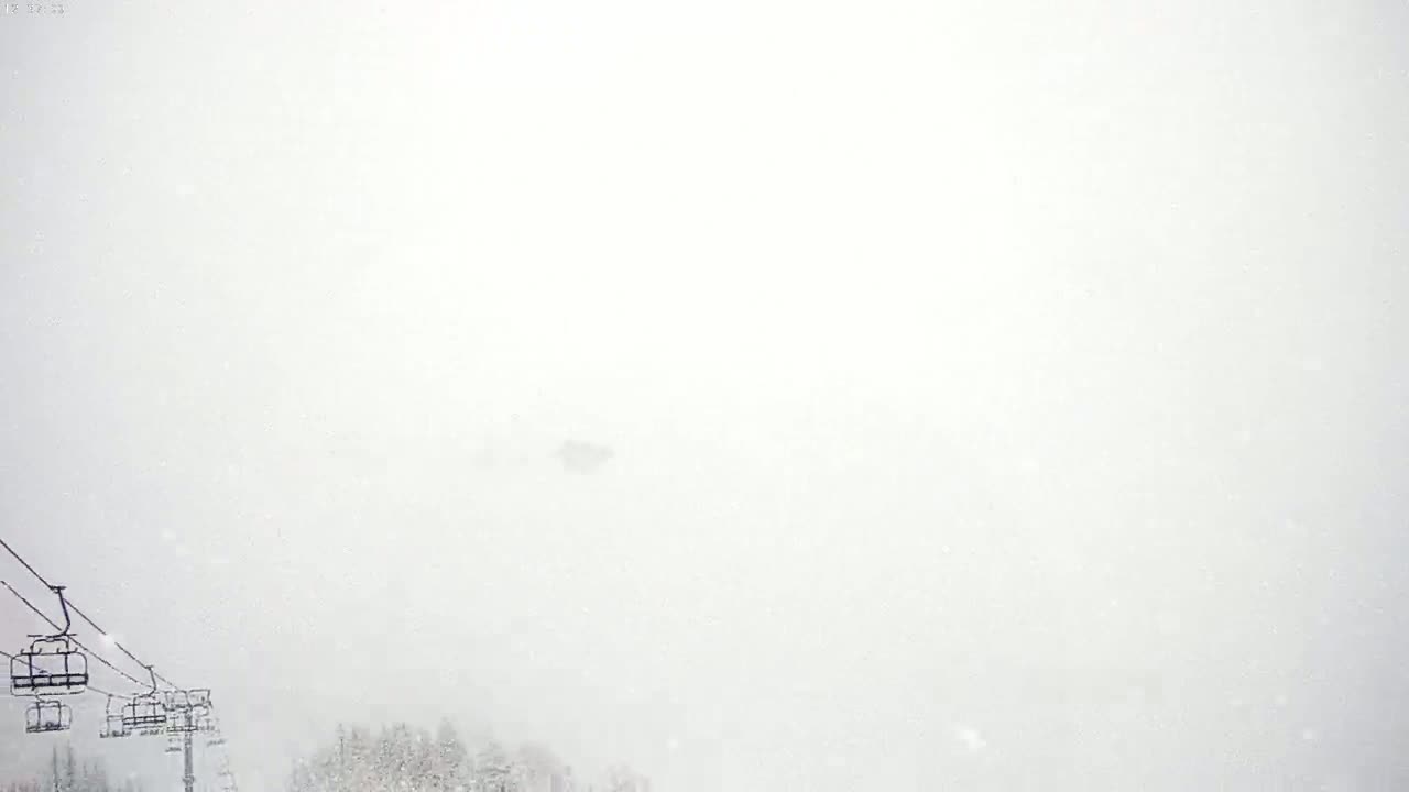 A ski lift is visible in a heavy snowstorm.