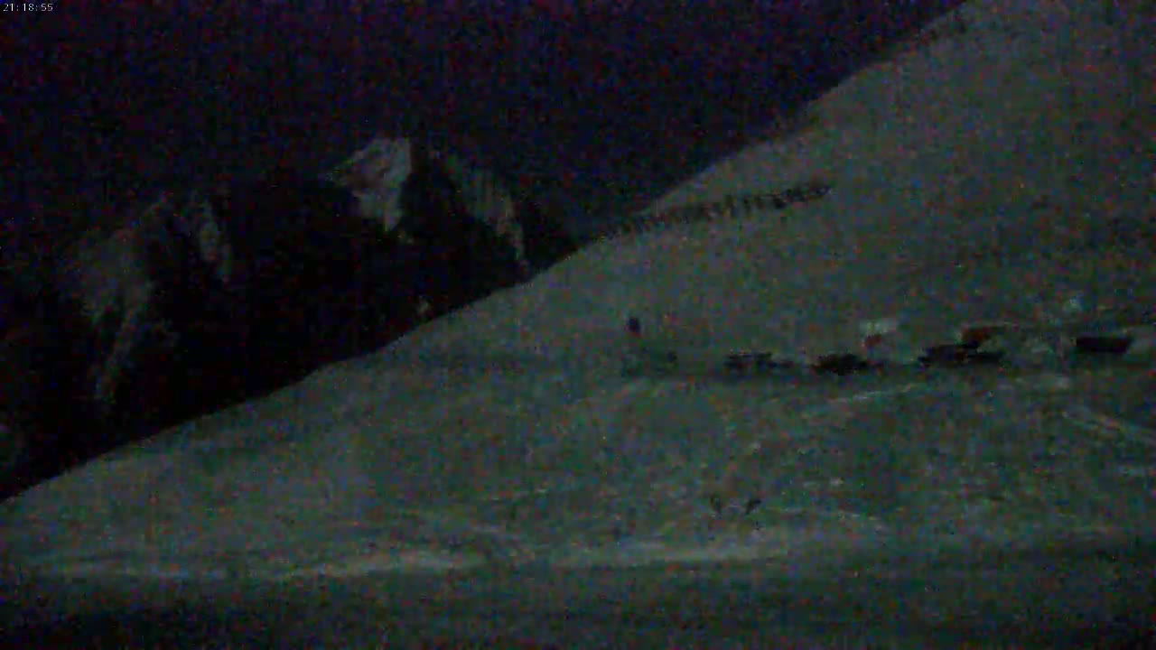 A dark, snowy hillside is visible at night.