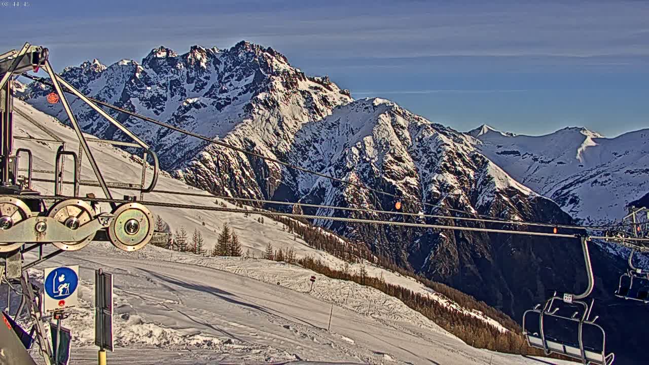 A snow-covered mountain range is viewed from a ski lift on a sunny day.