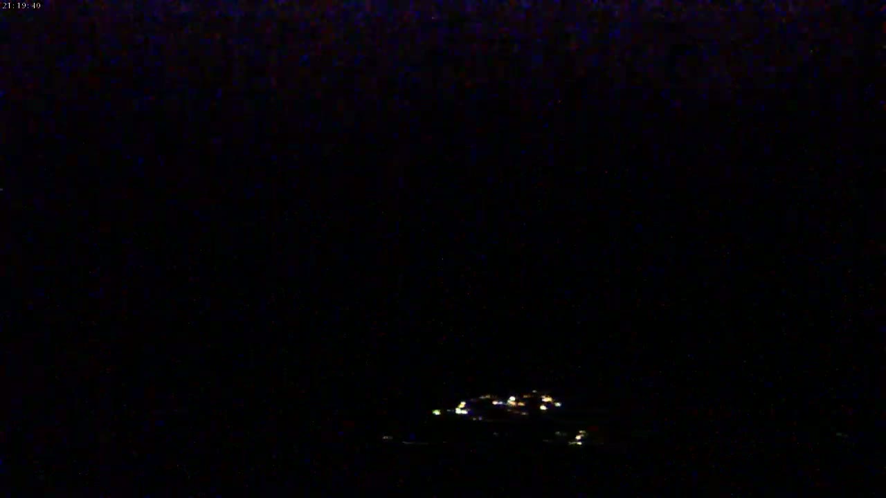 A cluster of faint lights is visible in the distance at night.