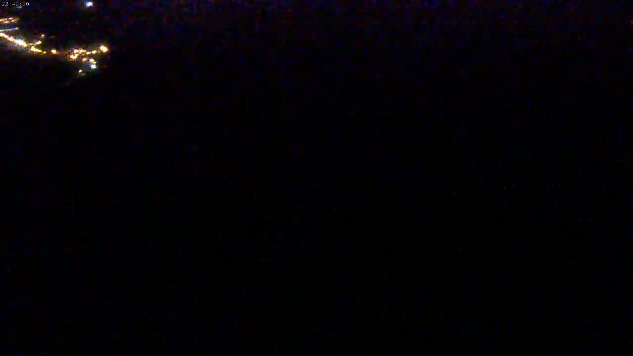 A nighttime view shows a few distant lights in the upper left corner of a mostly dark scene.