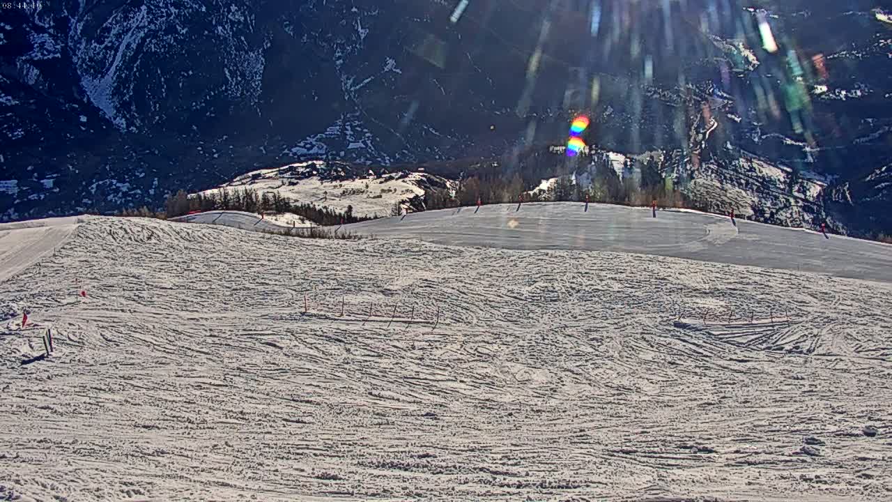 A sunny day on a snow-covered ski slope with a mountain in the background.