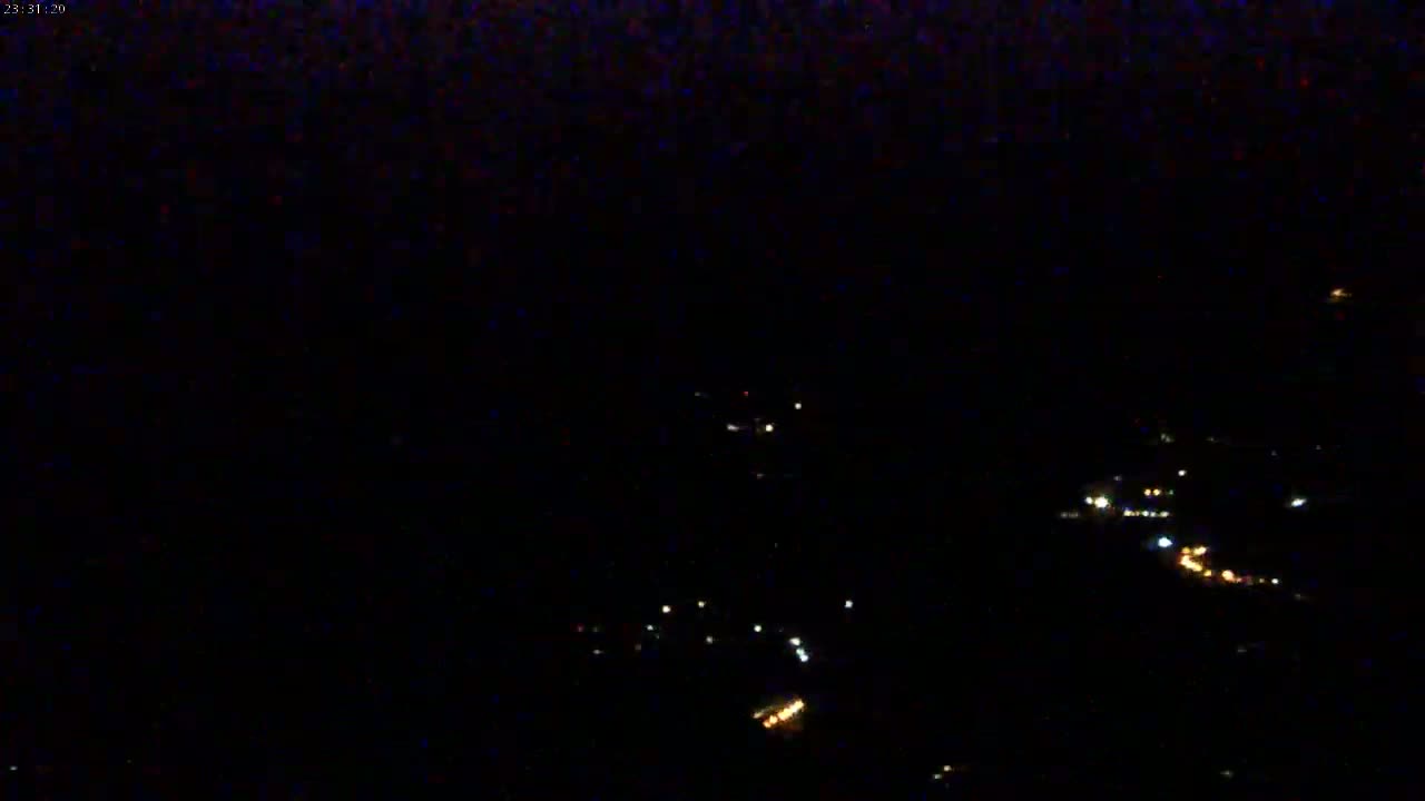 A nighttime long shot shows a cluster of distant lights in the dark.