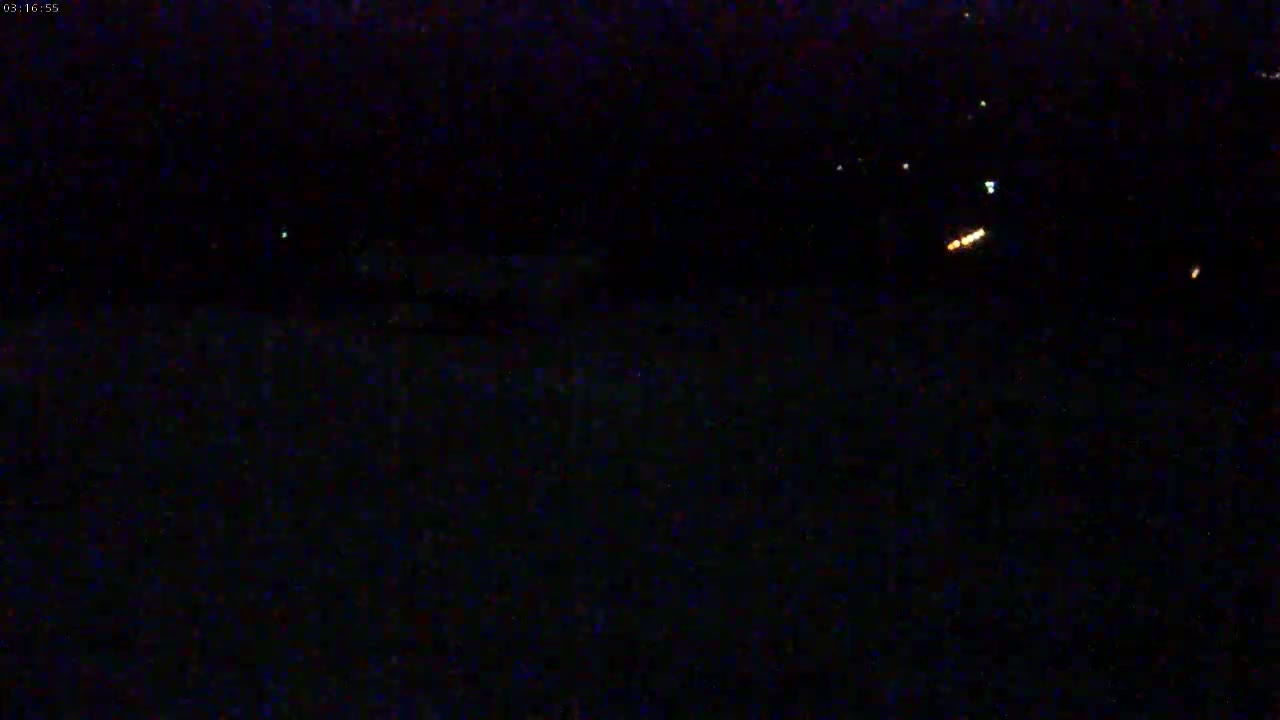 A dark, nighttime scene shows a few faint lights in the distance.