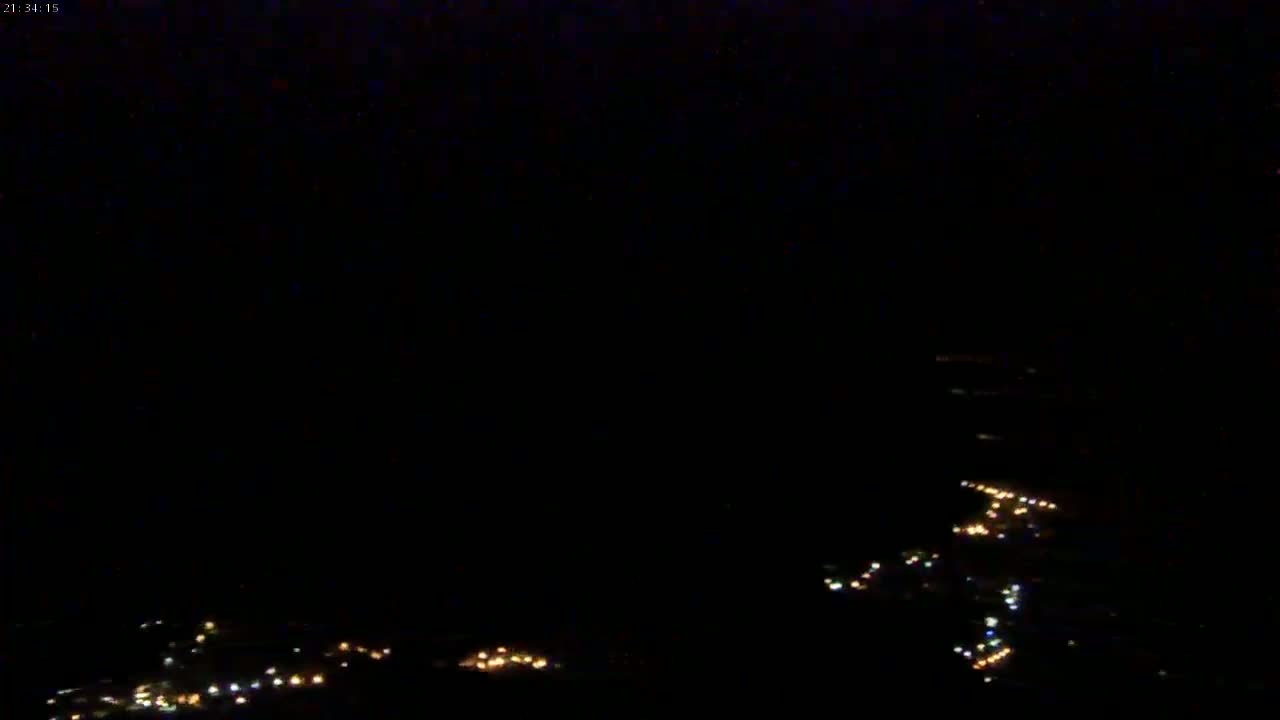 A nighttime, aerial view shows a scattering of faint, distant lights across a dark landscape.