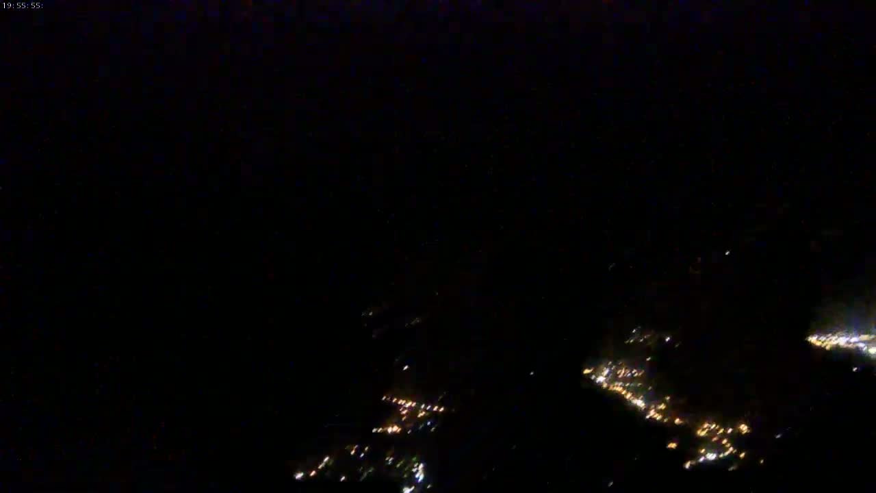A nighttime aerial view shows scattered city lights below in the darkness.