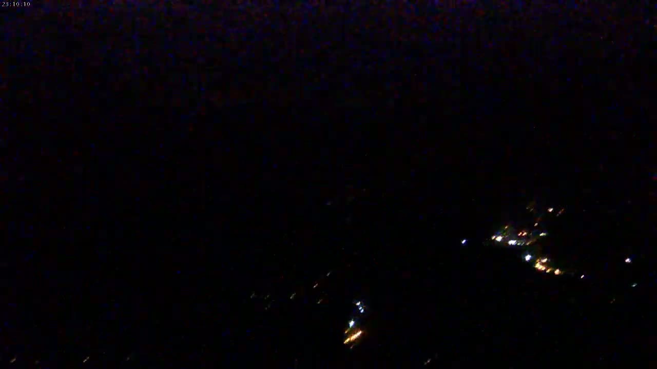 A nighttime, high-angle view shows a few scattered lights in the distance on what appears to be a landmass.