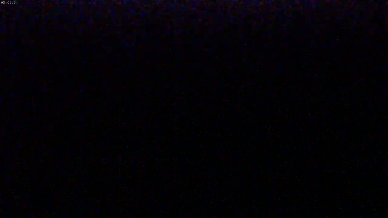The image shows an extremely dark, mostly black field with faint speckles of blue and red.