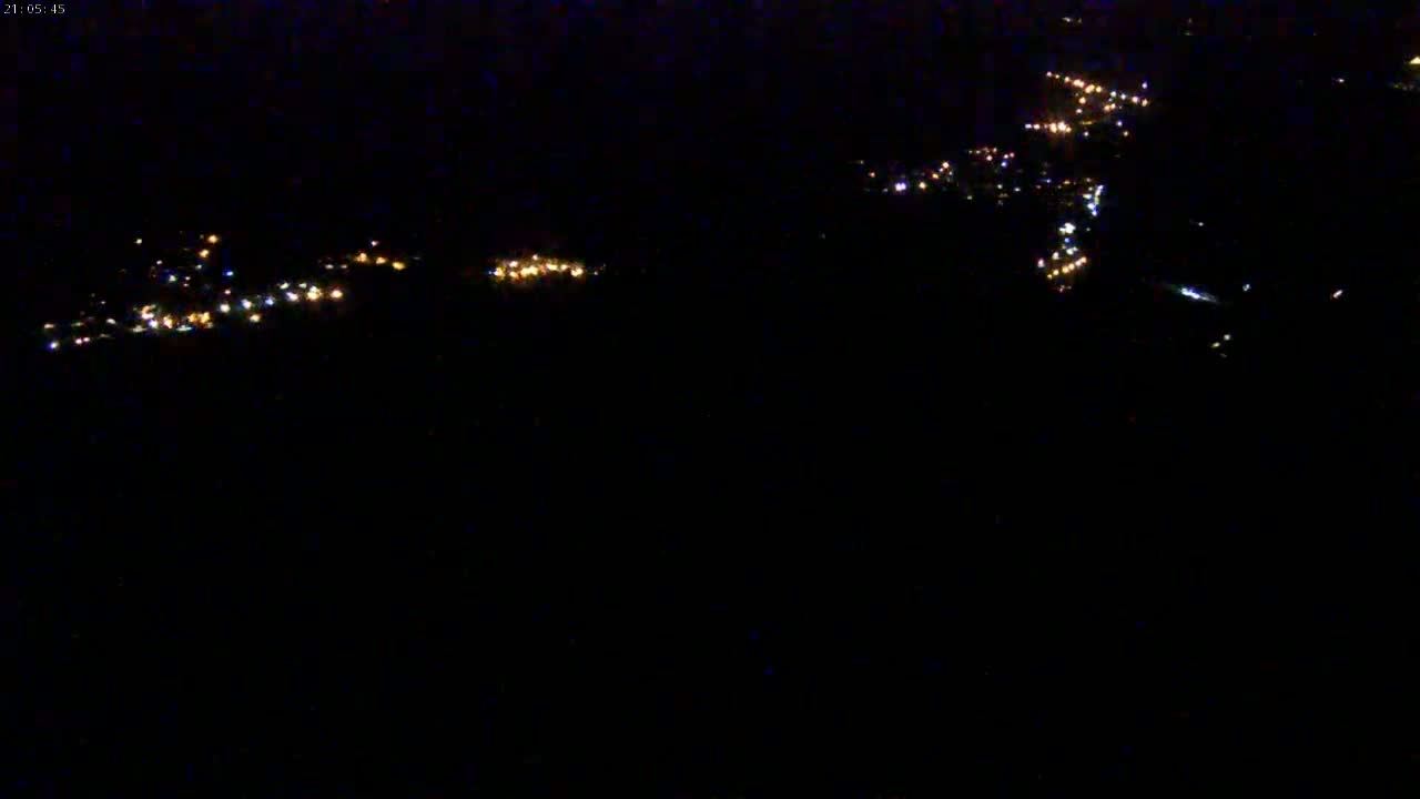 A nighttime aerial view shows scattered lights from a town or village below.