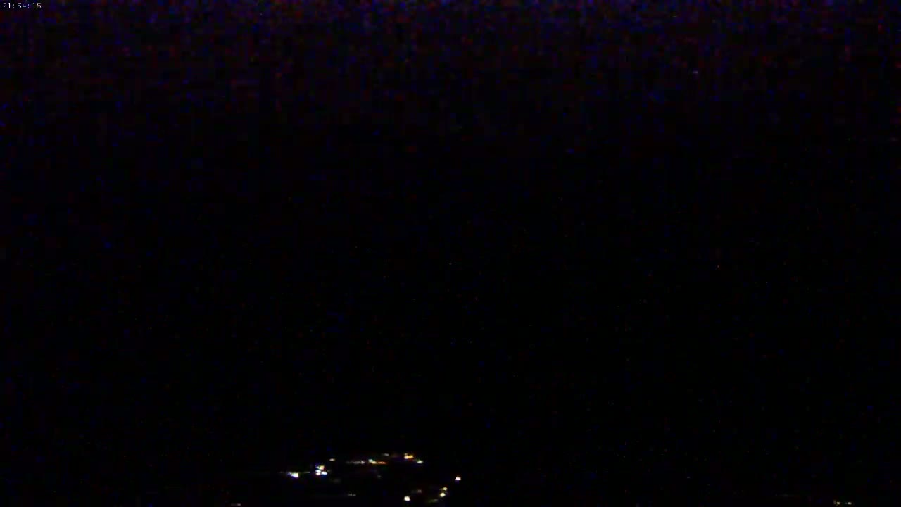 A nighttime long shot shows a few faint lights at the bottom of a very dark frame.