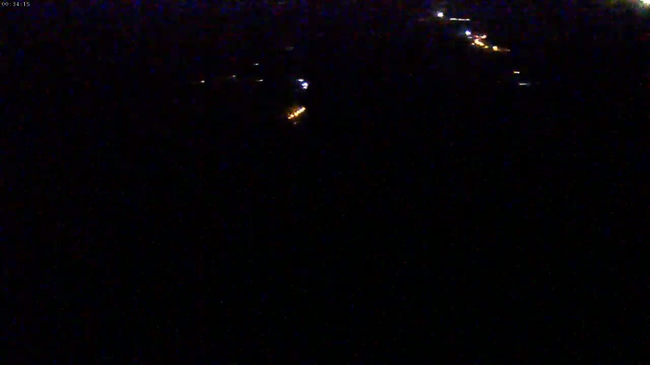 A nighttime view shows a scattering of distant, faint lights in the darkness.