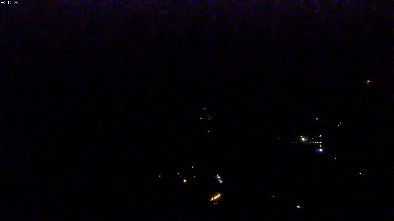 A nighttime, long-range view shows a scattering of faint lights on a dark landscape.