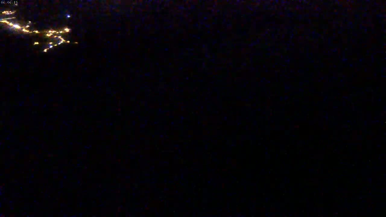 A nighttime aerial view shows a scattering of small, distant lights in the dark.