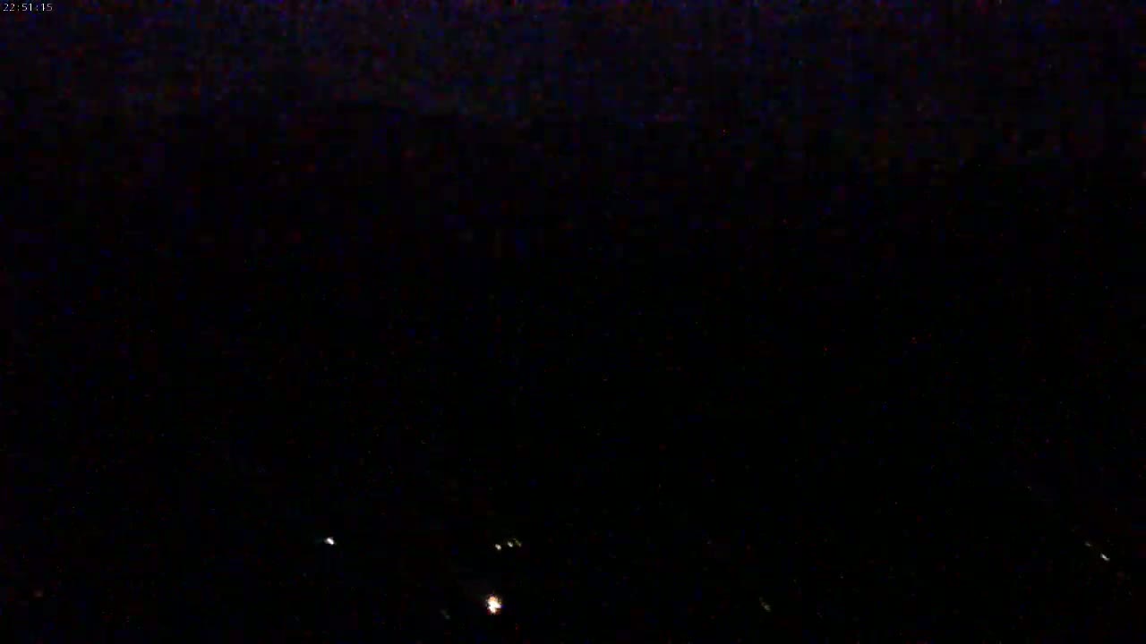 A nighttime, dark image shows a few distant, faint lights against an overwhelmingly black background.