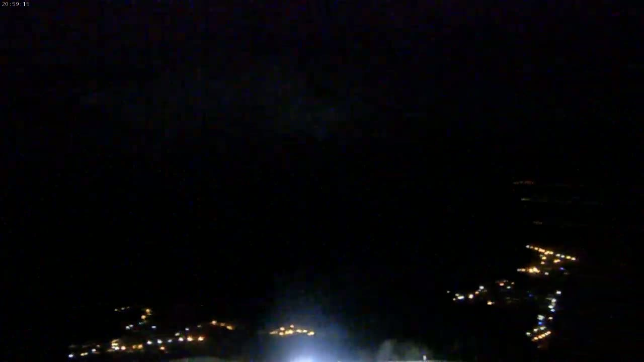 A nighttime aerial view shows a scattering of small, faint lights spread across a dark landscape.