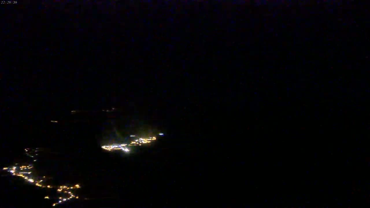 Scattered clusters of small, faint lights are visible on a dark, nighttime landscape.