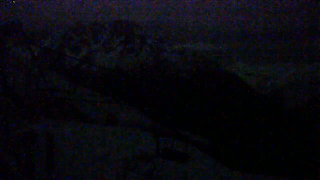 A dark, nighttime scene shows indistinct shapes possibly of land or structures under a cloudy sky.