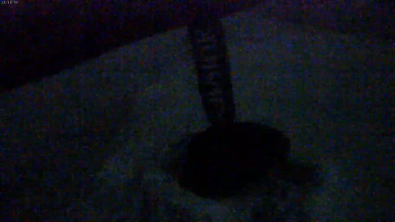 A dark, blurry image shows a dark object resembling a handle and a round base sitting on a dark surface.