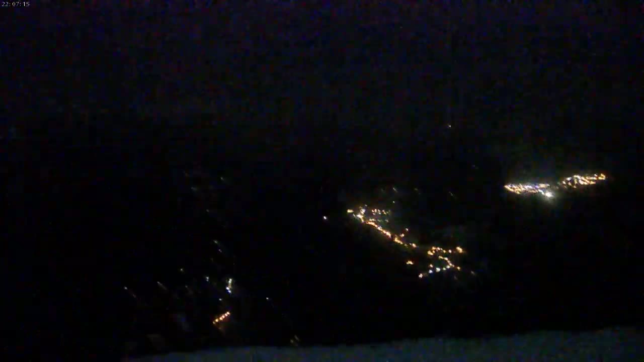 At night, small clusters of lights from a town or village are visible from a distance in the dark.