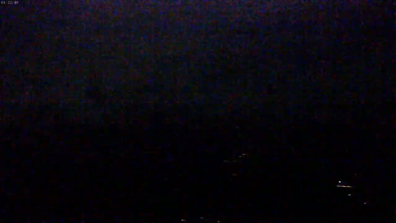 A dark, nighttime scene shows a few distant, faint lights on the horizon.