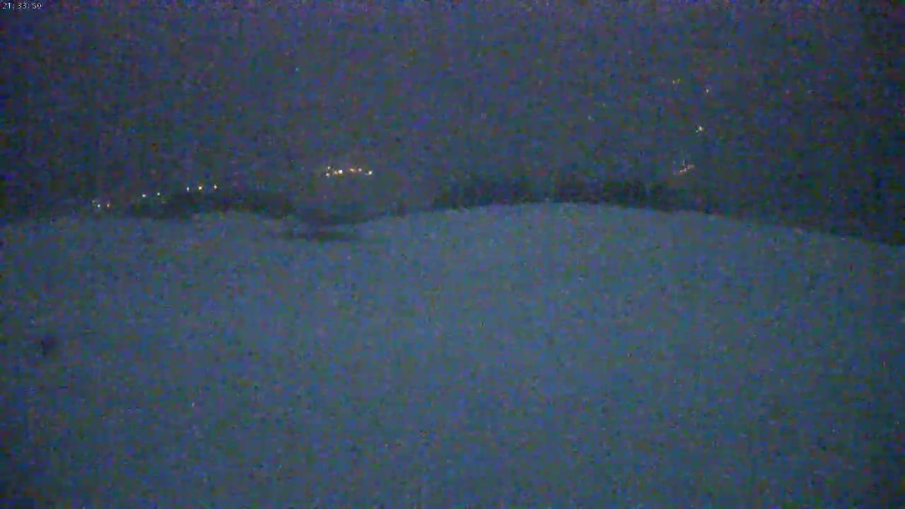 A nighttime, snowy landscape is visible with faint lights in the distance.