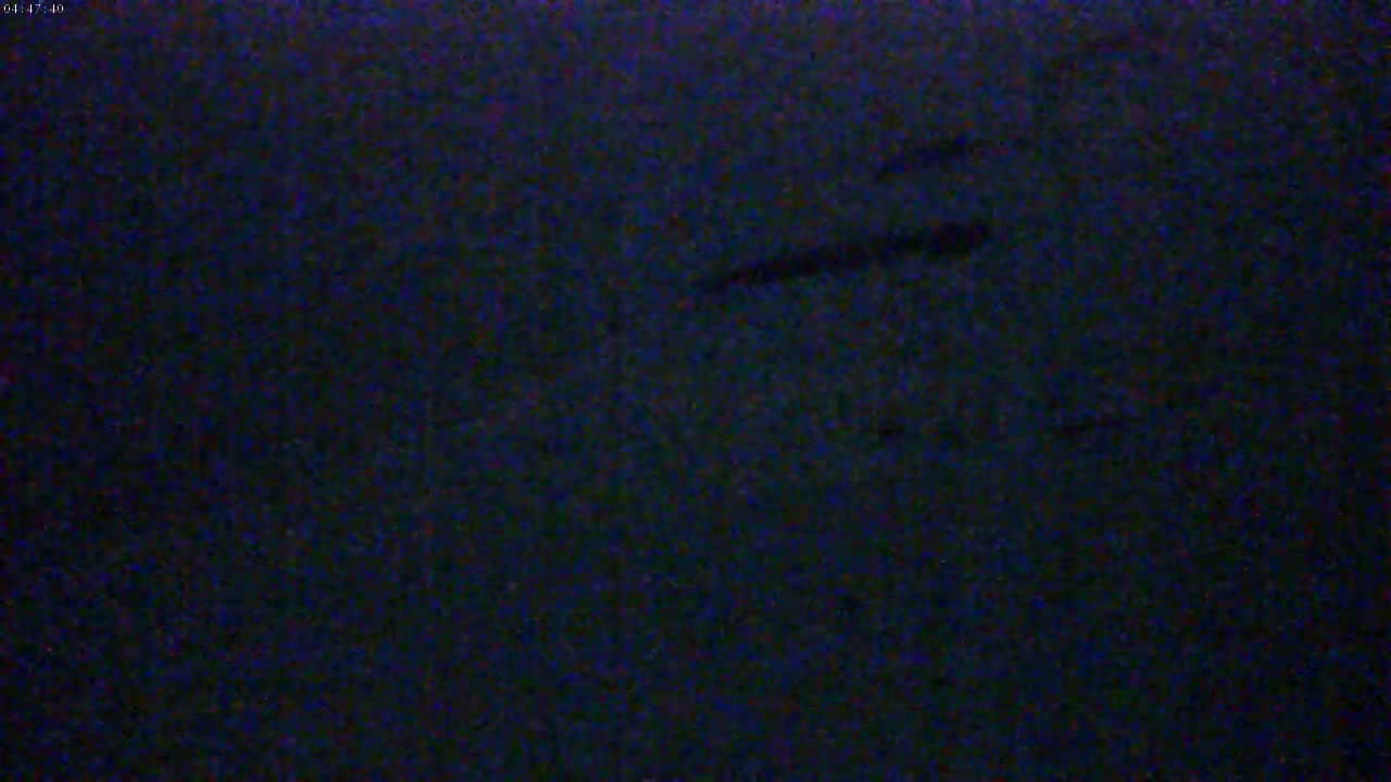 The image shows a dark, possibly nighttime, scene with faint, indistinct shapes that could be shadows or objects.