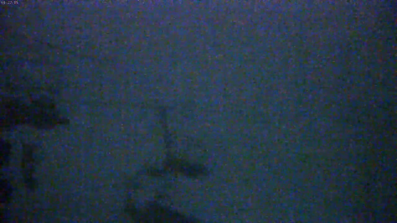 A dark, blurry nighttime image shows indistinct shapes that could be objects or structures in snowy or hazy conditions.