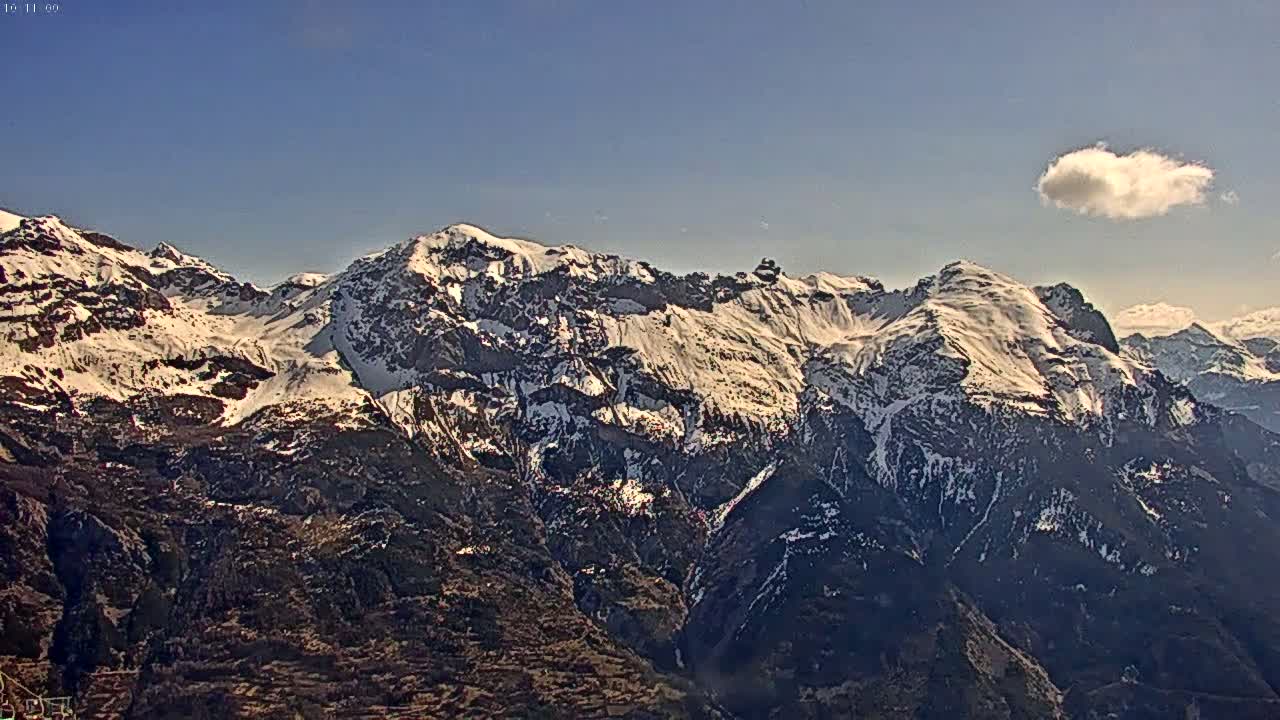 A snow-capped mountain range is visible under a clear blue sky with a single small cloud.