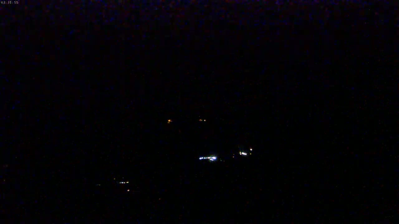 A nighttime long shot shows a few distant lights in the dark.