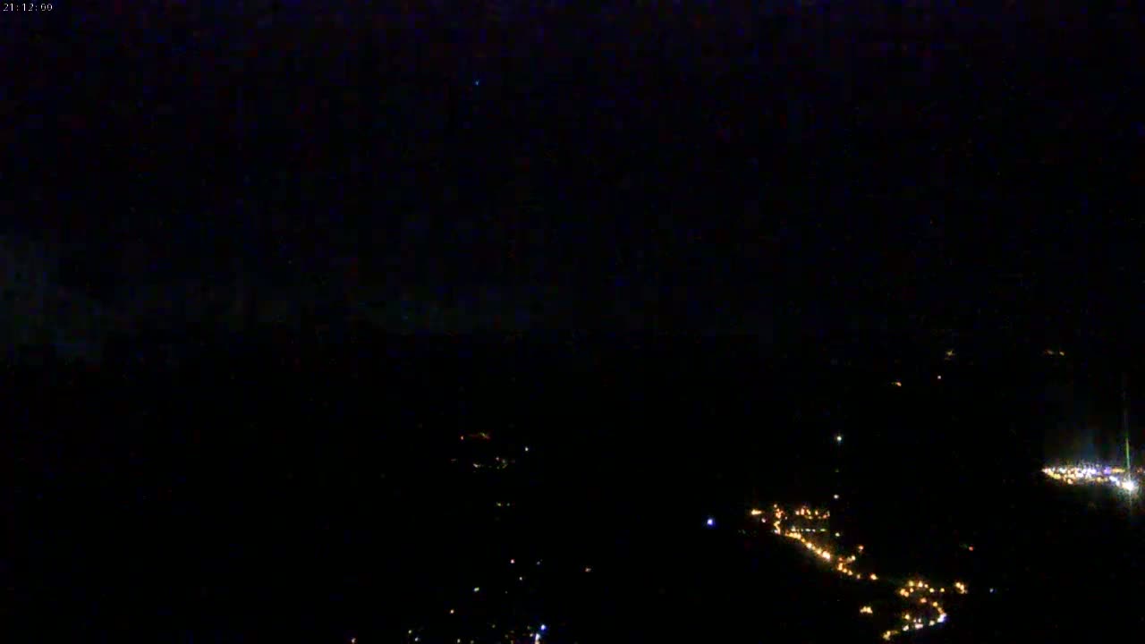 A nighttime, high-angle view shows a dark landscape sparsely dotted with small, distant lights.