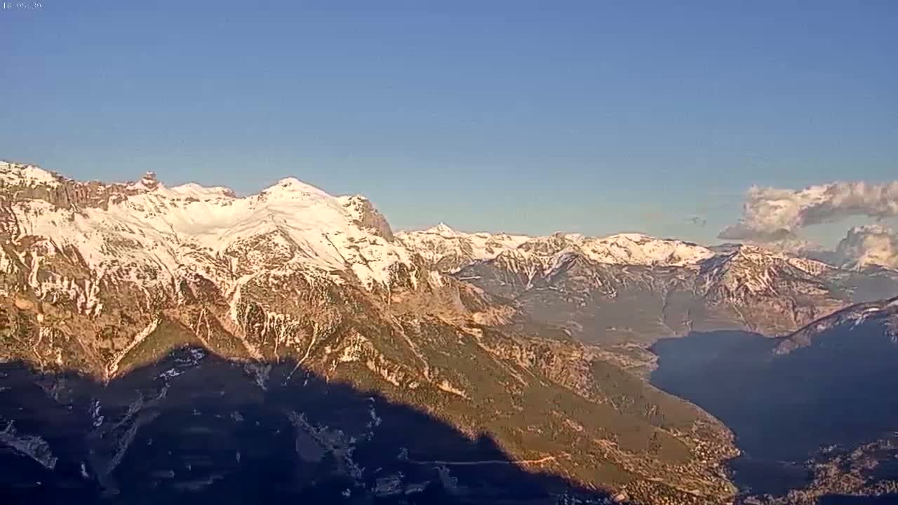 A long range view shows snow-capped mountains under a mostly clear blue sky with a few clouds.