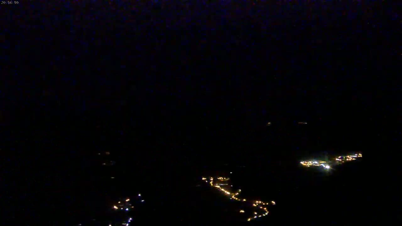 A nighttime aerial view shows several clusters of small, scattered lights on a dark landscape.
